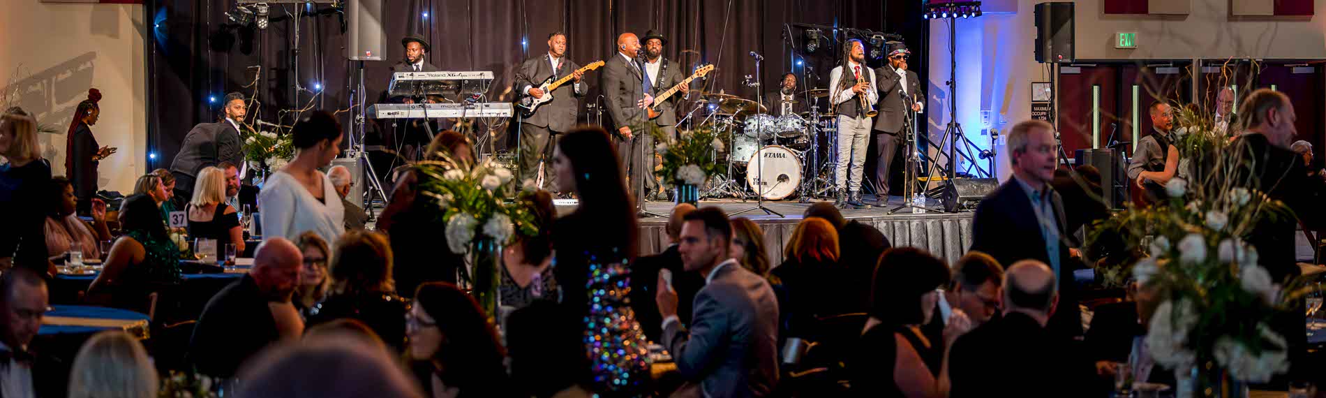 A band plays at the legacy ball as people eat and enjoy conversation.