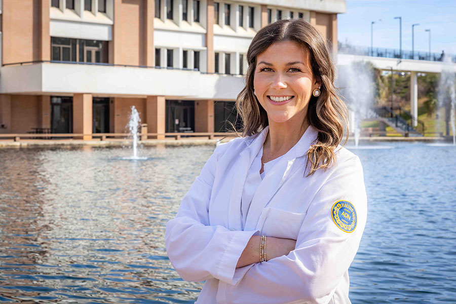 Sarah Carter stands in front of the reflecting pond outside of the 5000 building