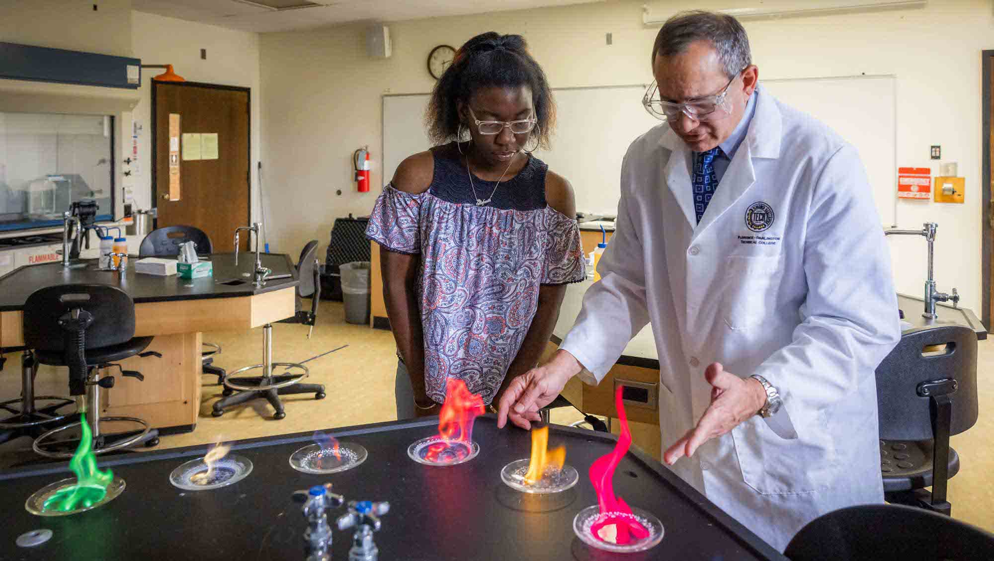 A Chemistry professor demonstrating to a student how different elements create different color fires.