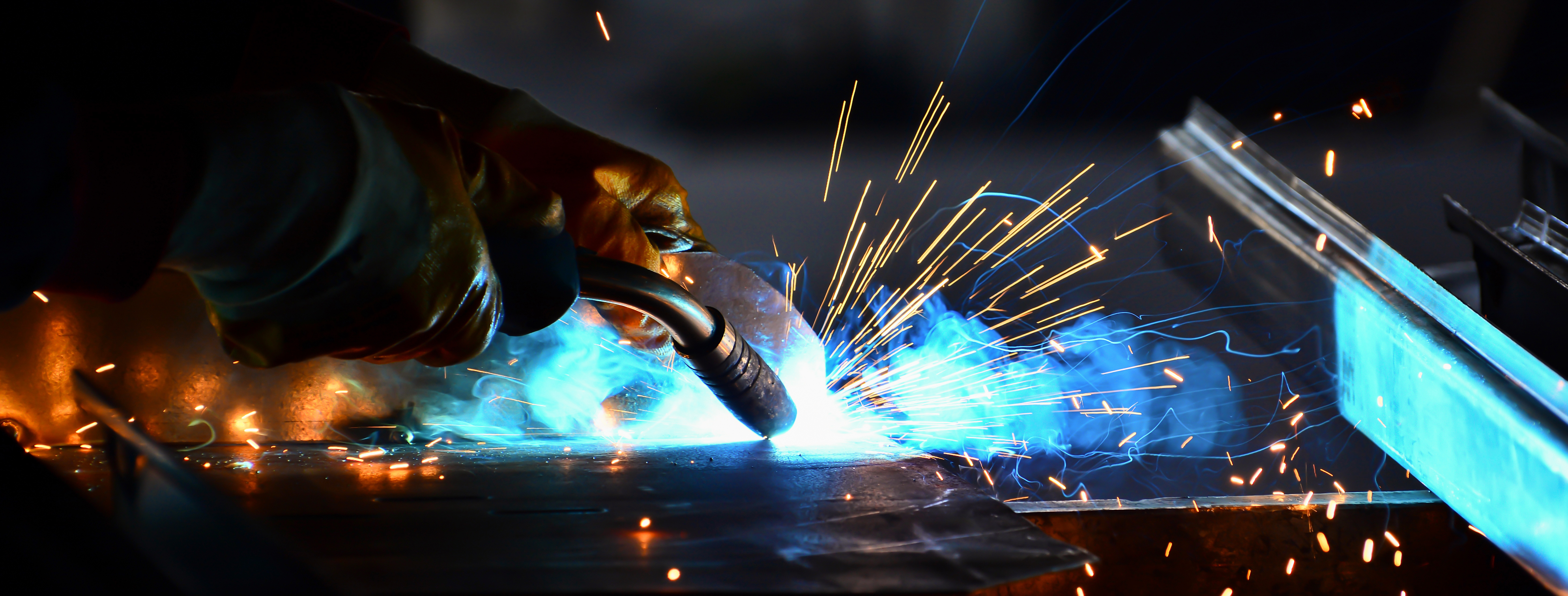 A close up image of a welder in action with fire and sparks