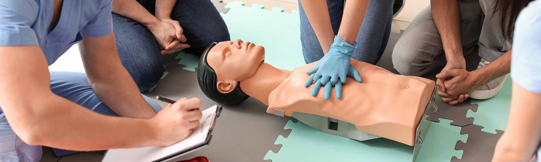 A group of students trains on a CPR manikin.