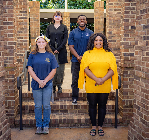 four student government officers are picture standing between columns